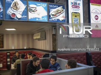 Iranian youths sit in a fast-food restaurant in the holy city of Qom 145Km (90 miles) south of Tehran on March 10, 2022. (