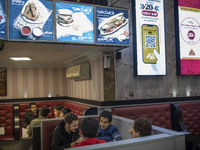 Iranian youths sit in a fast-food restaurant in the holy city of Qom 145Km (90 miles) south of Tehran on March 10, 2022. (