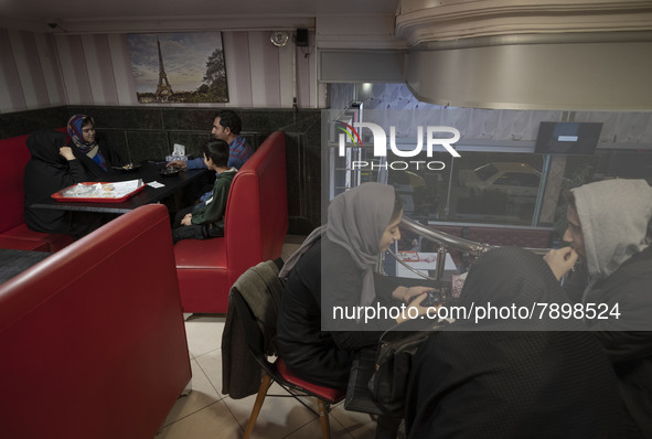 Iranian youths (R) and a family sit in a fast-food restaurant in the holy city of Qom 145Km (90 miles) south of Tehran on March 10, 2022. 