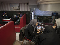 Iranian youths (R) and a family sit in a fast-food restaurant in the holy city of Qom 145Km (90 miles) south of Tehran on March 10, 2022. (