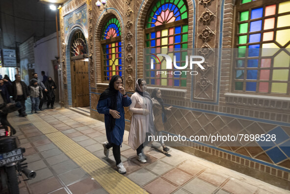 Three Iranian young women walk past a traditional restaurant in the holy city of Qom 145Km (90 miles) south of Tehran on March 10, 2022. 