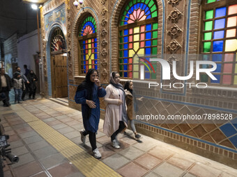 Three Iranian young women walk past a traditional restaurant in the holy city of Qom 145Km (90 miles) south of Tehran on March 10, 2022. (