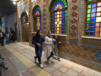 Three Iranian young women walk past a traditional restaurant in the holy city of Qom 145Km (90 miles) south of Tehran on March 10, 2022. (