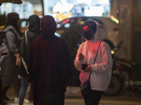 An Iranian young girl wearing a protective face mask looks on while standing out of a fast-food restaurant in the holy city of Qom 145Km (90...