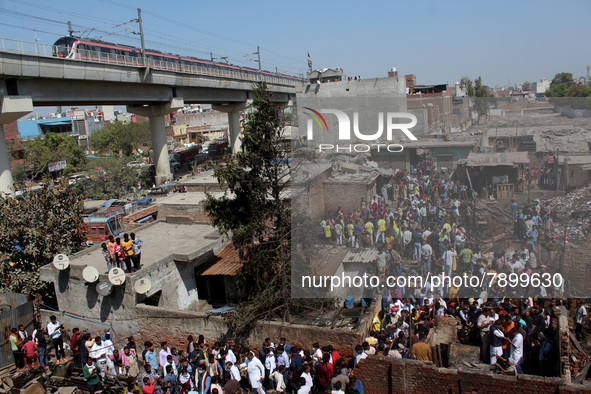 People gather as firemen try to douse a fire at shanties around Gokulpuri area in New Delhi, India on March 12, 2022. At least seven people...