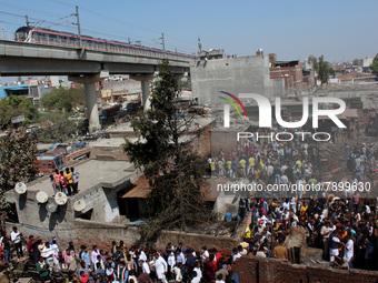 People gather as firemen try to douse a fire at shanties around Gokulpuri area in New Delhi, India on March 12, 2022. At least seven people...