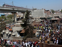 People gather as firemen try to douse a fire at shanties around Gokulpuri area in New Delhi, India on March 12, 2022. At least seven people...