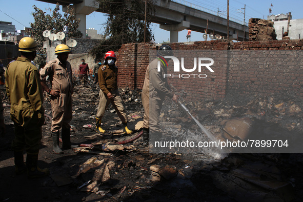 Firemen spray water across damaged homes after a fire broke out in a makeshift settlement area around Gokulpuri in New Delhi, India on March...