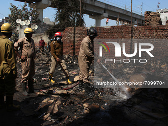 Firemen spray water across damaged homes after a fire broke out in a makeshift settlement area around Gokulpuri in New Delhi, India on March...