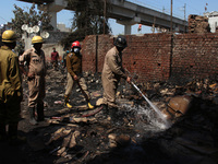 Firemen spray water across damaged homes after a fire broke out in a makeshift settlement area around Gokulpuri in New Delhi, India on March...