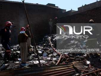 Firemen spray water across damaged homes after a fire broke out in a makeshift settlement area around Gokulpuri in New Delhi, India on March...