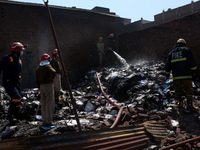 Firemen spray water across damaged homes after a fire broke out in a makeshift settlement area around Gokulpuri in New Delhi, India on March...