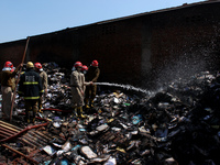 Firemen spray water across damaged homes after a fire broke out in a makeshift settlement area around Gokulpuri in New Delhi, India on March...