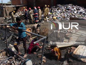 People search for their belongings as firemen lay a hose pipe across damaged shanties after a fire broke out in a makeshift settlement area...