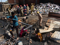 People search for their belongings as firemen lay a hose pipe across damaged shanties after a fire broke out in a makeshift settlement area...