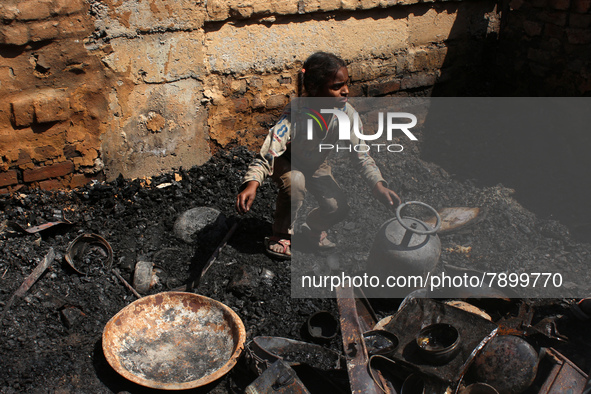 A girl salvages belongings among the charred remains of her home after a fire broke out in a makeshift settlement area around Gokulpuri in N...