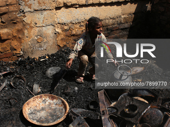 A girl salvages belongings among the charred remains of her home after a fire broke out in a makeshift settlement area around Gokulpuri in N...