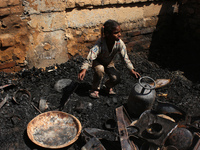 A girl salvages belongings among the charred remains of her home after a fire broke out in a makeshift settlement area around Gokulpuri in N...