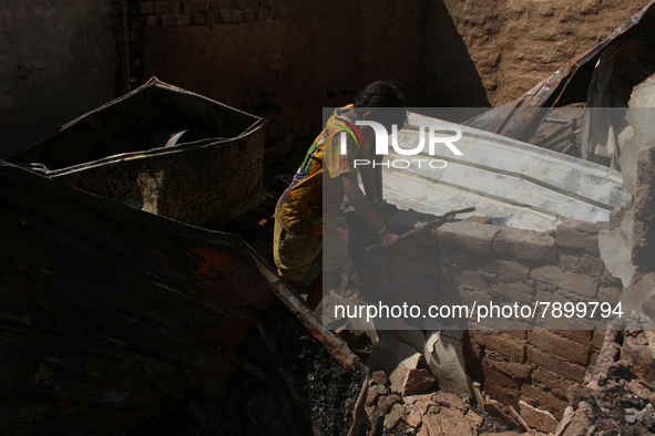 A boy salvages belongings among the charred remains of his home after a fire broke out in a makeshift settlement area around Gokulpuri in Ne...