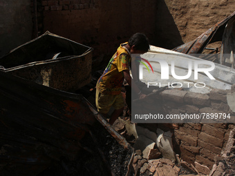 A boy salvages belongings among the charred remains of his home after a fire broke out in a makeshift settlement area around Gokulpuri in Ne...