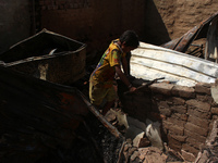 A boy salvages belongings among the charred remains of his home after a fire broke out in a makeshift settlement area around Gokulpuri in Ne...