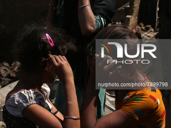 Girls react as they stand outside the charred remains of their home after a fire broke out in a makeshift settlement area around Gokulpuri i...