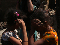 Girls react as they stand outside the charred remains of their home after a fire broke out in a makeshift settlement area around Gokulpuri i...