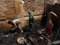 Girls salvage belongings among the charred remains of their home after a fire broke out in a makeshift settlement area around Gokulpuri in N...