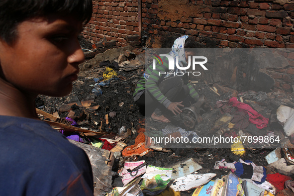 A girl salvages belongings among the charred remains of her home after a fire broke out in a makeshift settlement area around Gokulpuri in N...