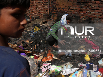 A girl salvages belongings among the charred remains of her home after a fire broke out in a makeshift settlement area around Gokulpuri in N...