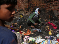 A girl salvages belongings among the charred remains of her home after a fire broke out in a makeshift settlement area around Gokulpuri in N...