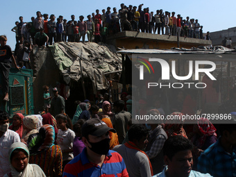 People gather to listen as Delhi's Chief Minister Arvind Kejriwal addresses during his visit to the site after a fire broke out in a makeshi...