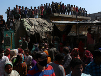 People gather to listen as Delhi's Chief Minister Arvind Kejriwal addresses during his visit to the site after a fire broke out in a makeshi...