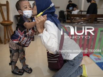 Mrs. ENI RAFFASYA's mother kisses her child who seems to be able to stand with the aid of a prosthetic leg. COKI TOBING, the owner of a pros...