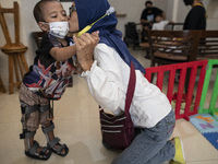 Mrs. ENI RAFFASYA's mother kisses her child who seems to be able to stand with the aid of a prosthetic leg. COKI TOBING, the owner of a pros...