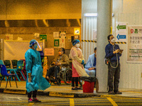 Nurses and paramedics stand guard near a makeshift triage area at Princess Margaret hospital, while patients wait there too, in Hong Kong, C...