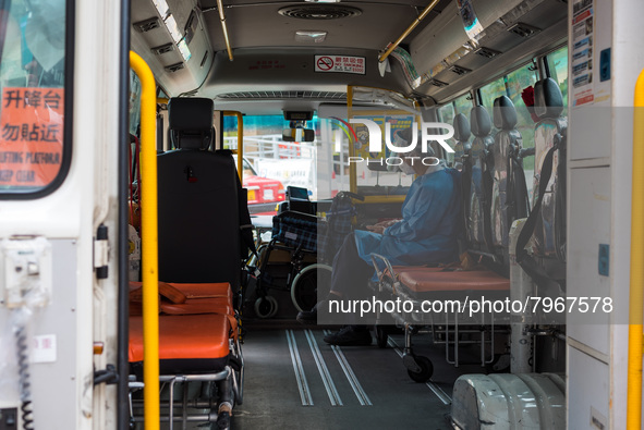 A paramedic checks his phone while waiting in an ambulance bus to transfer patients at United Christian Hospital, in Kwun Tong, in Hong Kong...