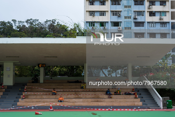 Construction workers take a break on a football ground completely cordoned off for social distancing, in Hong Kong, China, on March 24, 2022...