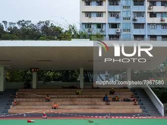 Construction workers take a break on a football ground completely cordoned off for social distancing, in Hong Kong, China, on March 24, 2022...