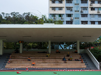 Construction workers take a break on a football ground completely cordoned off for social distancing, in Hong Kong, China, on March 24, 2022...