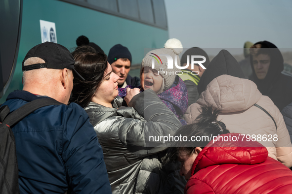 An Ukrainian child is seen crying in her mother's arms, among many other Ukrainian citizens at the transit point for refugees in Palanca, so...