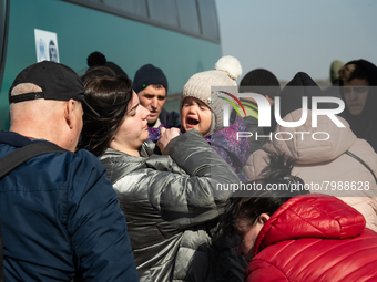 An Ukrainian child is seen crying in her mother's arms, among many other Ukrainian citizens at the transit point for refugees in Palanca, so...