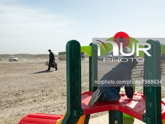 Ukrainian child is seen play while a man ig going to get the bus, at the transit point for refugees in Palanca, south Moldova, on 2022-03-27...