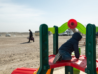 Ukrainian child is seen play while a man ig going to get the bus, at the transit point for refugees in Palanca, south Moldova, on 2022-03-27...