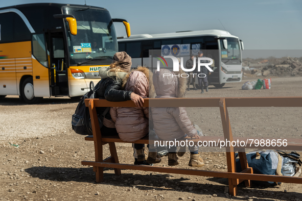 An Ukrainian mother and her two twin daughters is seen waiting for the bus at the transit point for refugees in Palanca, south Moldova, on 2...