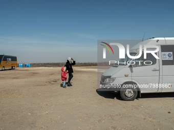 An Ukrainian mother and daughter are seen fighting agains the strong wind at the transit point for refugees in Palanca, south Moldova, on 20...