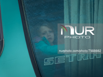 An Ukrainian girl is seen through the screen of a bus headed to Bucarest, Romania, at the transit point for refugees in Palanca, south Moldo...