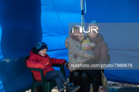 An Ukrainian mother and her two children are seen sitting inside a tent at the transit point for refugees in Palanca, south Moldova, on 2022...