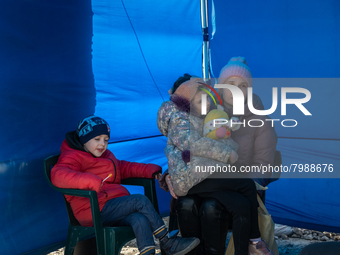 An Ukrainian mother and her two children are seen sitting inside a tent at the transit point for refugees in Palanca, south Moldova, on 2022...