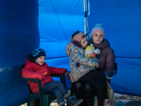 An Ukrainian mother and her two children are seen sitting inside a tent at the transit point for refugees in Palanca, south Moldova, on 2022...